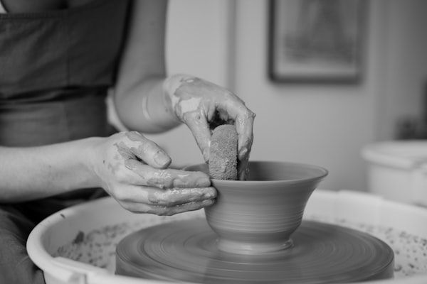 Hands working clay on a pottery wheel