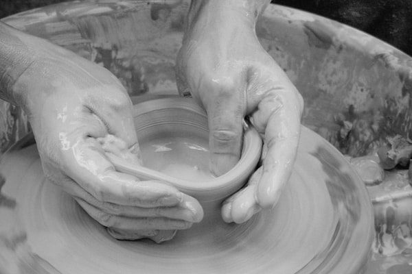 Hands forming clay on the wheel